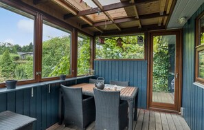 A covered patio with wicker furniture, a table with a kettle, and potted plants. - 2 bedroom nice home in Juelsminde (Juelsminde)