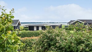 A modern residential area with houses and a large body of water in the background. - 2 bedroom nice home in Juelsminde (Juelsminde)