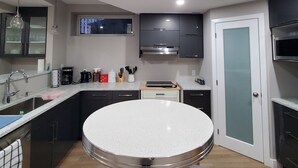 A modern kitchen with a central island, built-in appliances, and a dining area with a round table and two chairs. - Separate Entrance Basement Suite (Winnipeg)