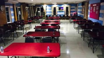 A conference room with multiple tables and chairs, a tiled floor, and a blue and red wall.