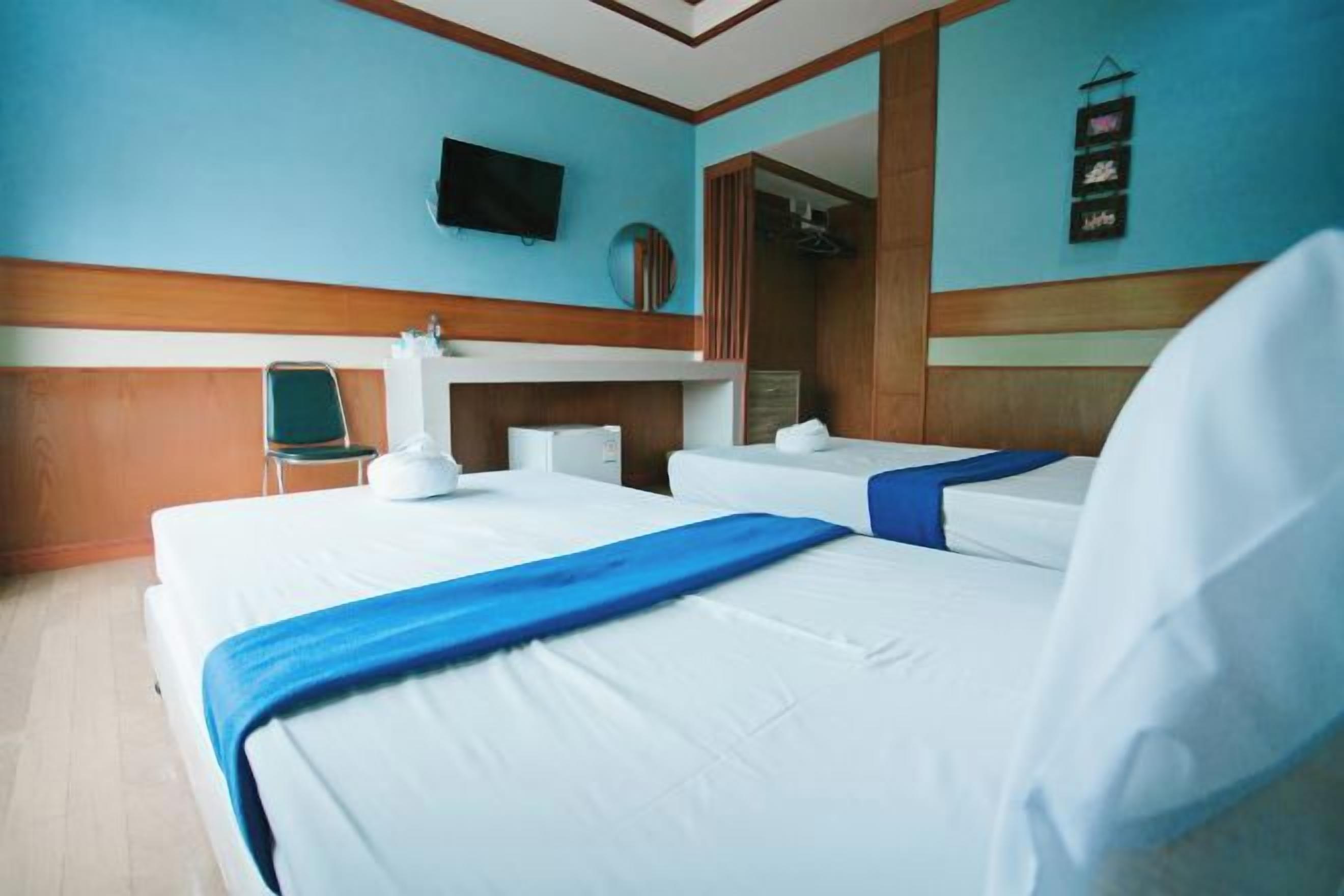 Habitación de hotel con dos camas, un televisor, un espejo y un panel de pared de madera.