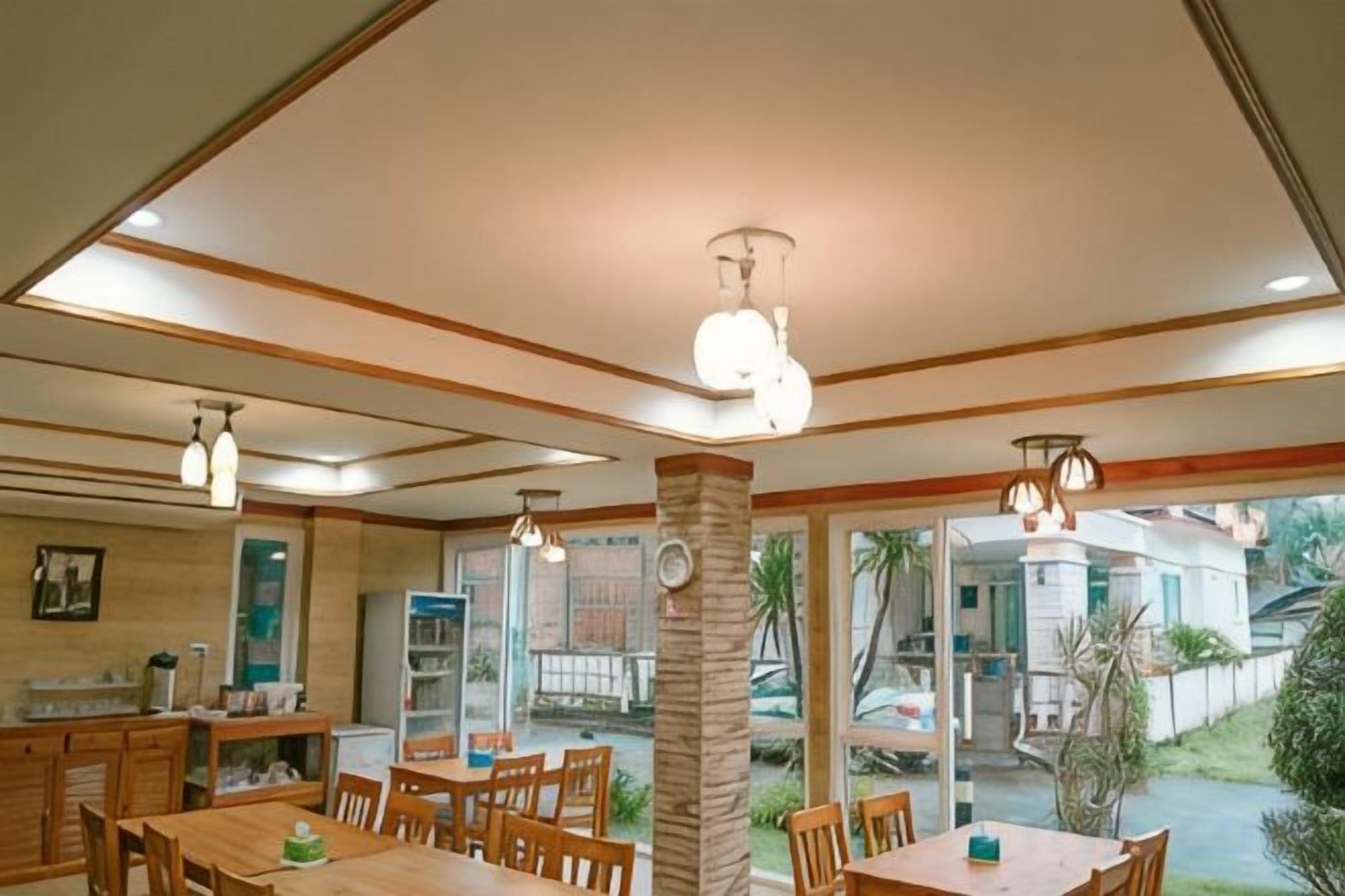 Un espace repas avec des tables et des chaises en bois, un coin cuisine avec des placards et une vue sur l’extérieur.