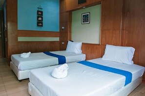 Quarto de hotel com duas camas de solteiro, cabeceira de madeira, prateleira na parede e quadro emoldurado.