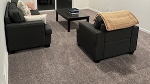 Ein Wohnzimmer mit einer Couch, einem Couchtisch und einem an der Wand montierten Fernseher.