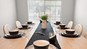 A dining table set for six with black and beige plates, bowls, and cutlery. - Casa Golden Retreat | Heated Pool • Hot Tub • BBQ (Casa Grande)