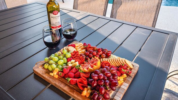 A table with a wine bottle, glasses, and a charcuterie board with various cheeses, fruits, and crackers. - Casa Golden Retreat | Heated Pool • Hot Tub • BBQ (Casa Grande)