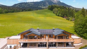 Una cabaña con balcón, ventanas amplias y paneles solares.
