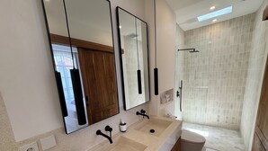 Une salle de bain moderne avec un grand miroir, deux lavabos, une douche et des toilettes.