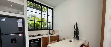 A modern kitchen with a refrigerator, stove, oven, and dining table with chairs.