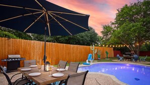 Un espace extérieur aménagé pour les repas, avec une piscine, une clôture en bois et du mobilier de jardin.