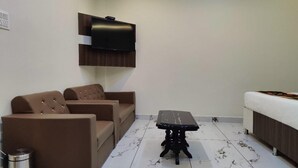Una sala de estar con un sofá, una mesita y un televisor fijado a la pared.