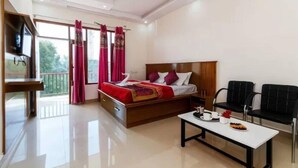 Una habitación de hotel con una cama, una mesita con un plato de comida, un televisor y un balcón con cortinas rojas.