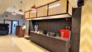 A reception area with a counter, a wooden cabinet, and a red Coca-Cola refrigerator. - Hotel Lakeview Chhatarpur (Chhatarpur)