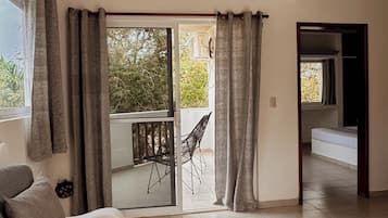 A spacious living area with a sofa, a dining table, and a sliding glass door leading to an outdoor patio.