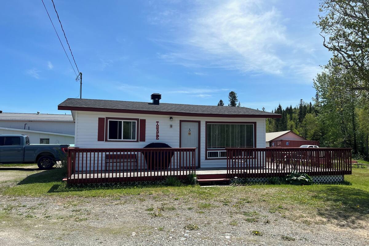 A single-story mobile home with a porch, a small deck, and a fenced yard.