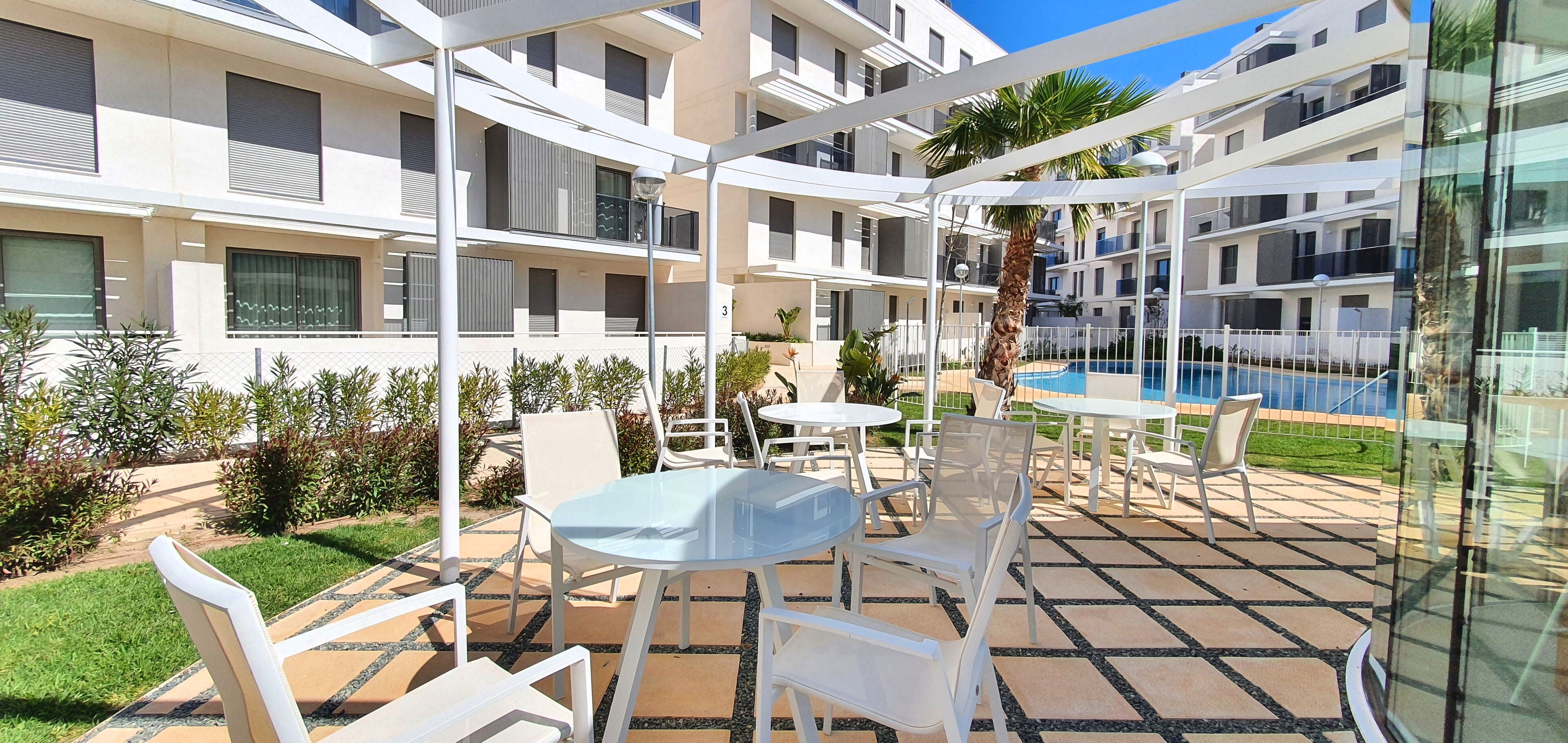 Un hotel moderno con terraza, piscina y un jardín bien cuidado.