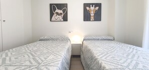 A room with two beds, a nightstand, and two wall-mounted artworks.