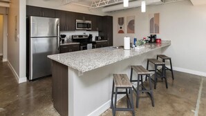 Una cocina moderna con electrodomésticos de acero inoxidable, encimera de granito y taburetes de bar.