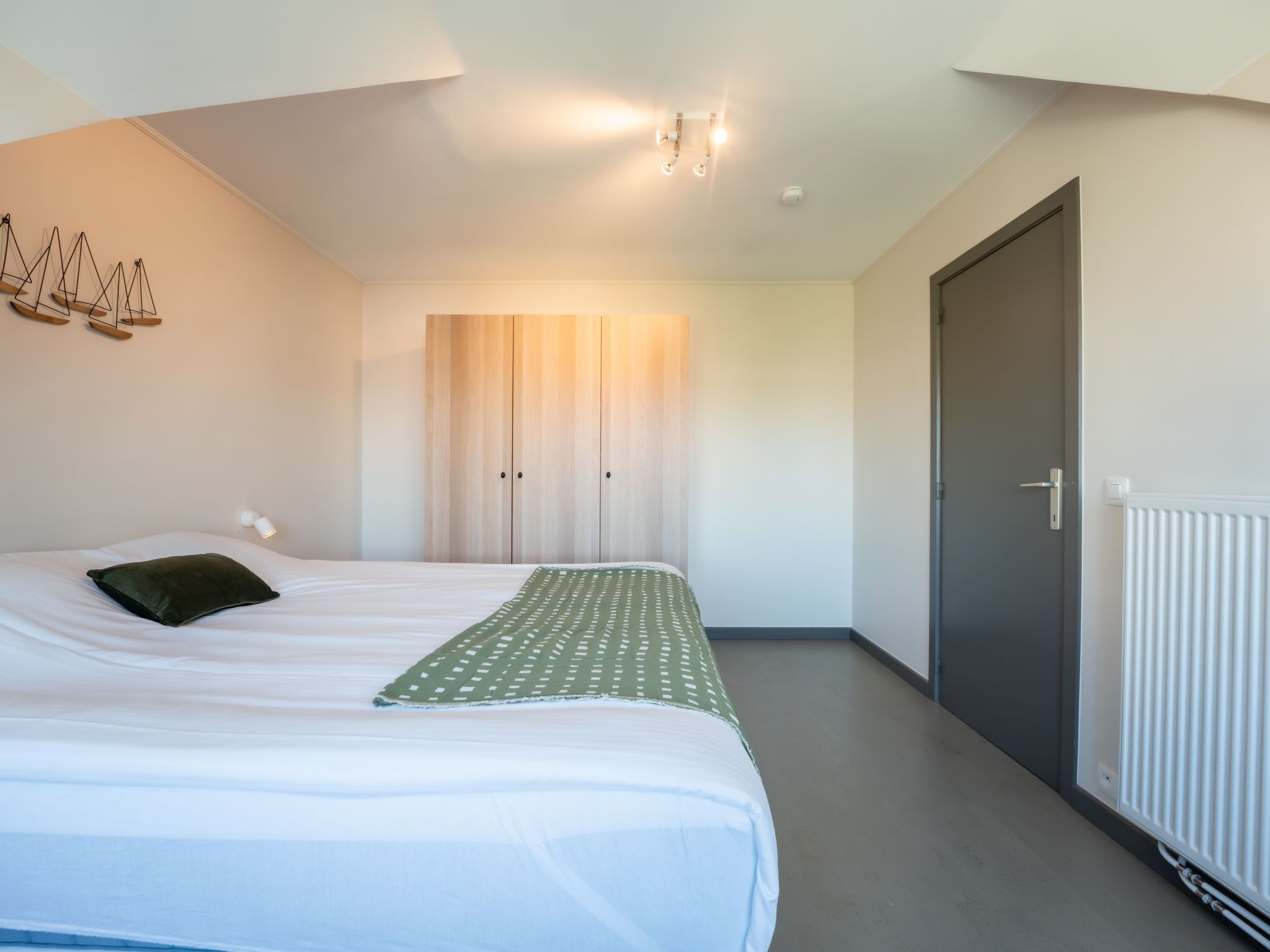 Une chambre moderne avec un lit, une armoire et un radiateur.