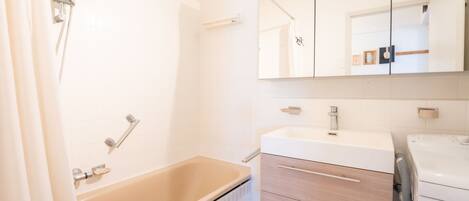 A bathroom with a bathtub, a sink, a mirror, and a shower.
