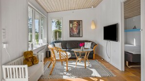 Ein gemütliches Wohnzimmer mit einer Couch, zwei Sesseln, einem Fernseher und einem Teddybären.