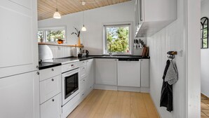 Eine moderne Küche mit weißen Schränken, einer Holzbalkendecke und einem Fenster, das natürliches Licht hereinlässt.
