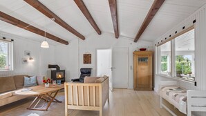 Ein gemütliches Wohnzimmer mit einer Holzdavonia, einem Couchtisch aus Holz, einem Kamin und einem großen Fenster mit Blick auf Grünflächen.