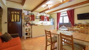 Una cuina acollidora amb bigues de fusta, una taula de dinar amb cadires i un sofà vermell.