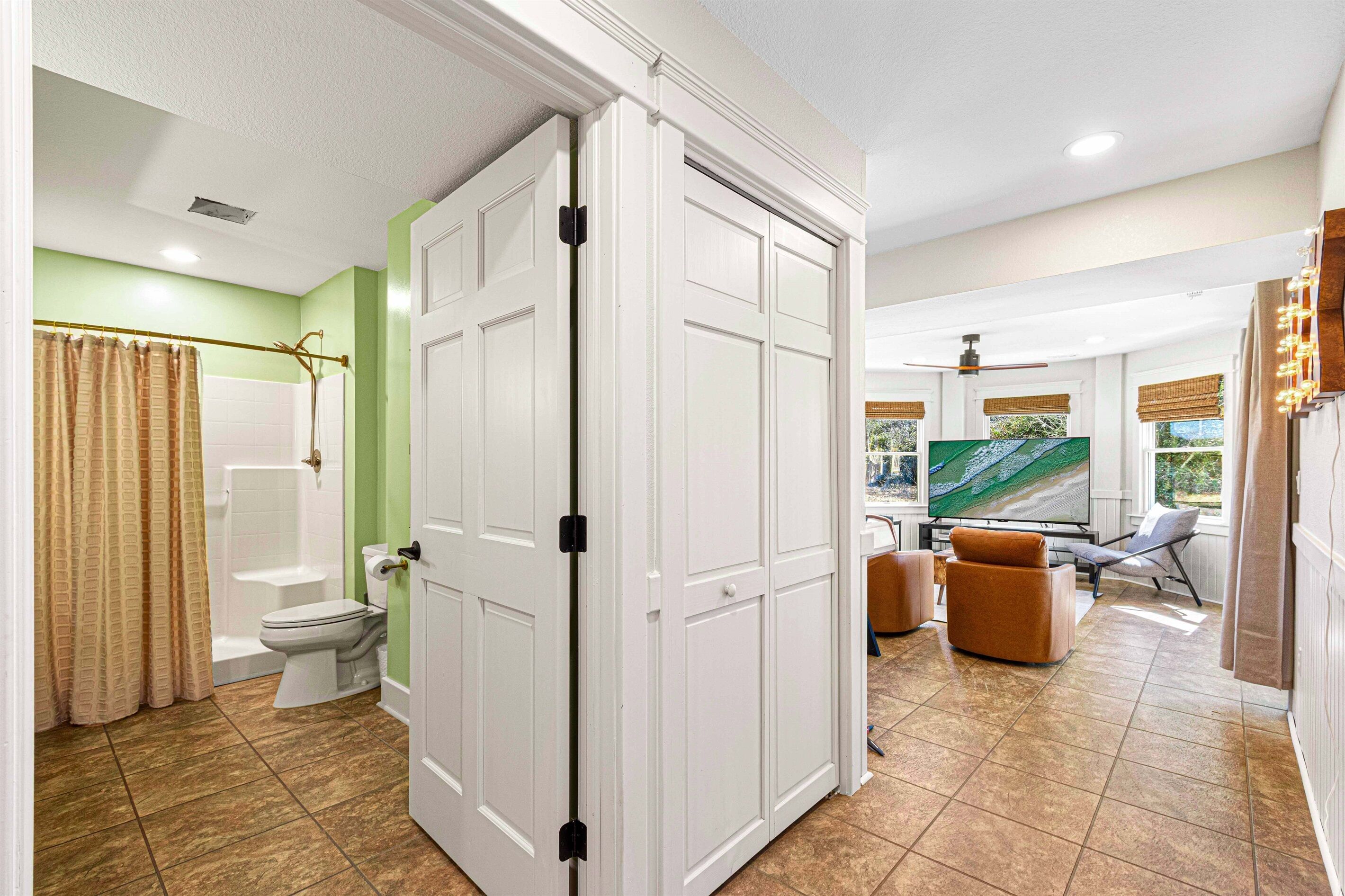 A bathroom with a toilet, shower, and a large mirror.