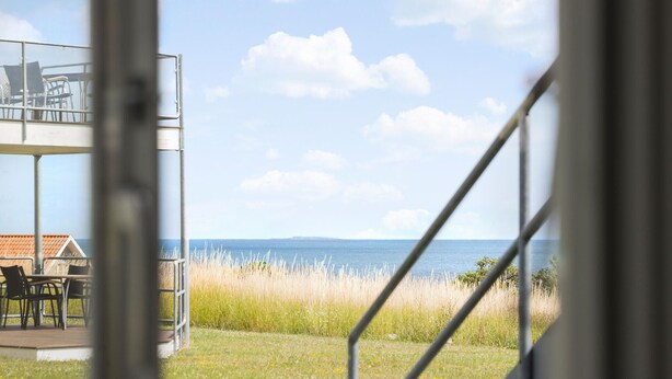 A view from a balcony overlooking a grassy area with a body of water and a distant shoreline.