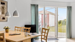 A modern dining area with a wooden table, chairs, and a television.