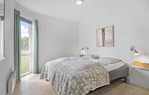 Relax in this serene bedroom with a large bed, bedside lamps, and a beautiful abstract painting.