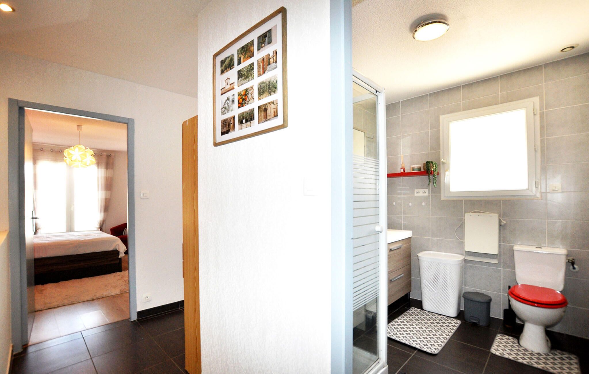 A hotel room with a bed, a hallway leading to a bathroom, and a wall-mounted photo collage.