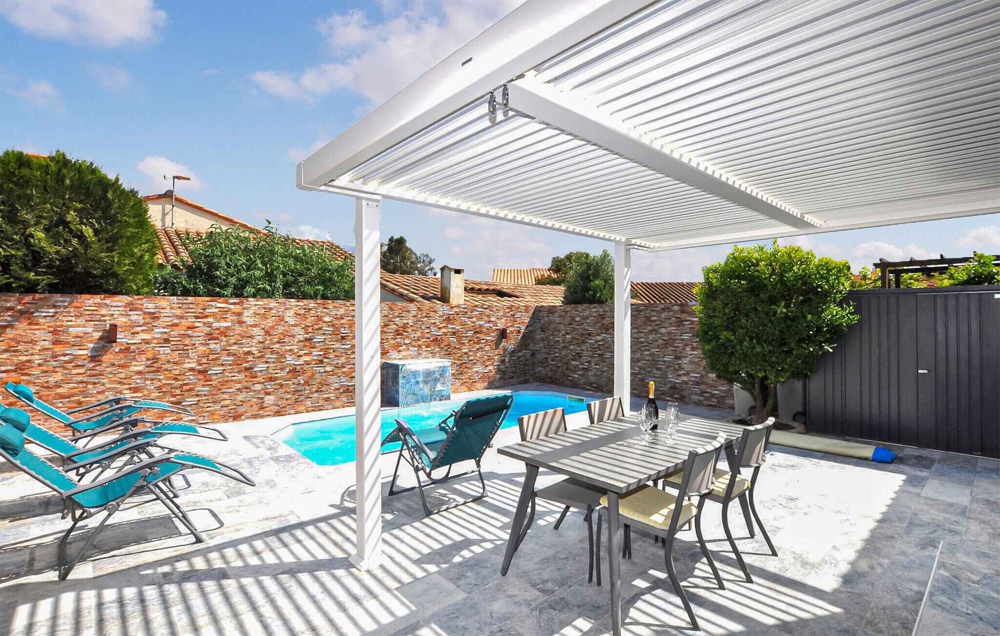 Un espace extérieur abrité comprenant une piscine, des chaises longues et une table.