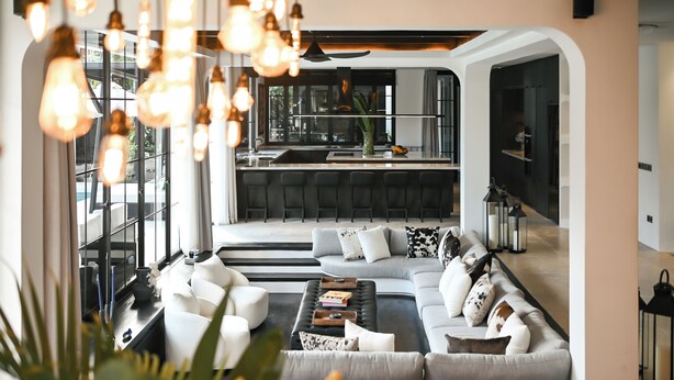 A modern living room with a large sofa, a coffee table, and a kitchen area in the background. - CARPEDIEM VILLA BALI operated by Villa Nila (Canggu)