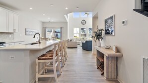 Une cuisine spacieuse dotée d’un îlot central, de tabourets de bar et d’un coin repas avec un canapé et des chaises.