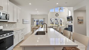 Une cuisine moderne avec des meubles blancs, un îlot central et un four encastré.