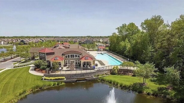Une grande maison avec une piscine, une fontaine et un étang.