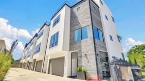 Un immeuble résidentiel moderne à plusieurs étages, doté d’un accès au garage, de grandes fenêtres et d’une façade en pierre.