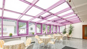 Una habitación soleada con techo alto, ventanas amplias y una mesa central con sillas.