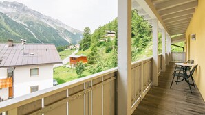 A balcony with a view of a mountainous landscape, wooden flooring, and a table with chairs. - Apartment Nr. 18 by Interhome (Sulden)