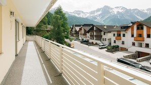 A balcony with a view of a mountain range, a row of houses, and a paved walkway. - Apartment Nr. 7 by Interhome (Sulden)