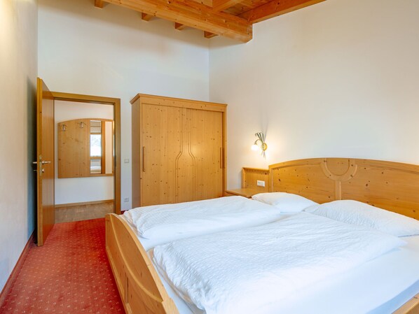 A bedroom with a wooden bed, a wardrobe, and a mirror.
