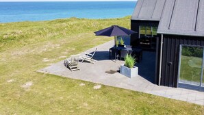 Une maison moderne dotée d’une terrasse offrant une vue sur la mer.