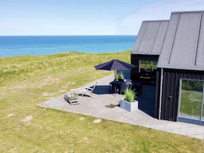 A modern house with a patio overlooking the sea.