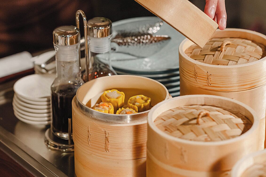 A tray with bamboo steamers containing dumplings and a salt shaker.
