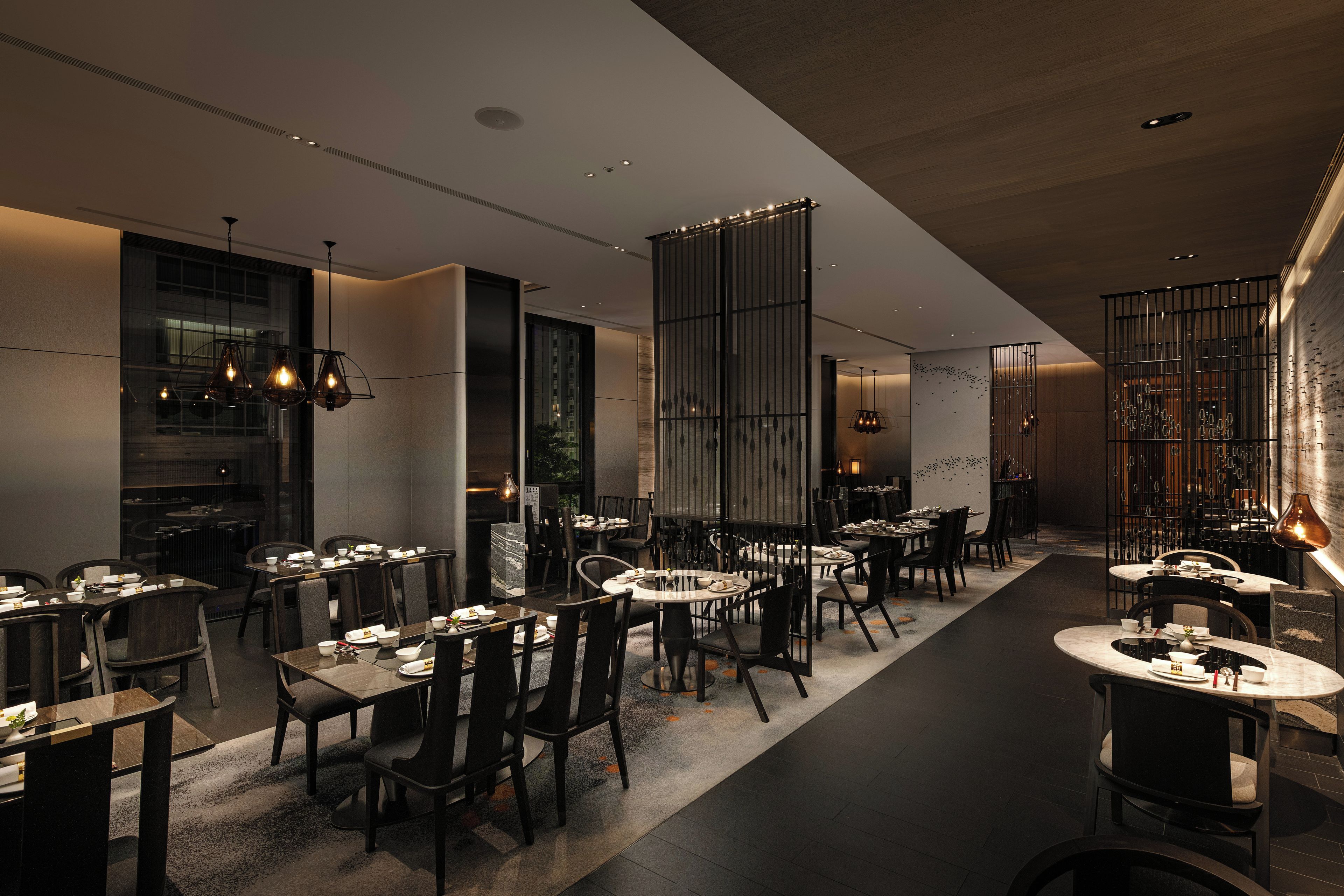 A modern restaurant interior with multiple dining tables and chairs, ambient lighting, and a view of the outside.