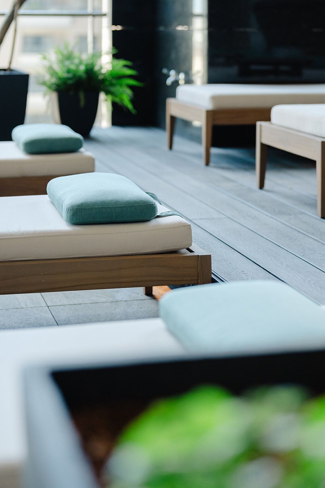A modern outdoor seating area with cushioned benches and a wooden floor.