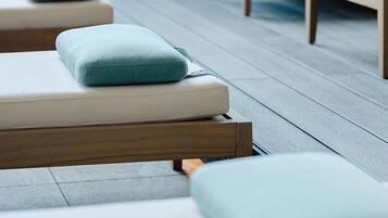 A modern outdoor seating area with cushioned benches and a wooden floor.