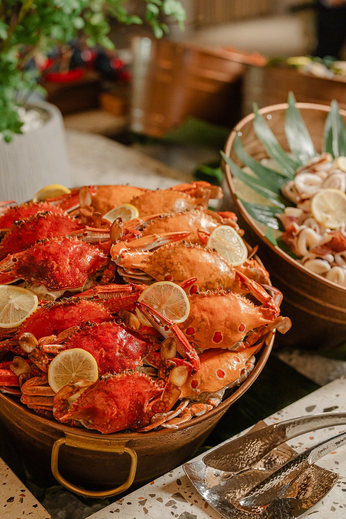 A large bowl filled with cooked crabs garnished with lemon slices.